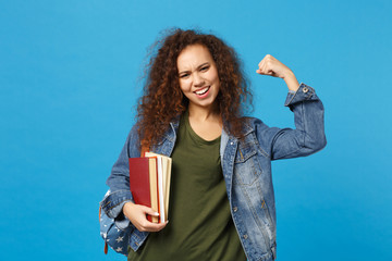 Young african american girl teen student in denim clothes, backpack hold books isolated on blue...