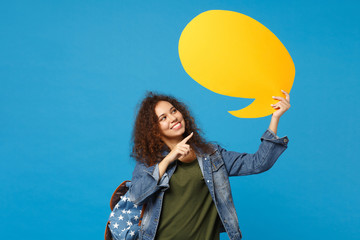 Young african american girl teen student in denim clothes, backpack hold say cloud isolated on blue...