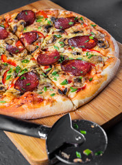 Pepperoni Pizza with Mozzarella cheese, salami, pepper, Spices and mushrooms. Italian pizza on Dark grey black slate background
