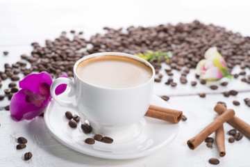 white cup of coffee on a background of scattered coffee beans on a white background
