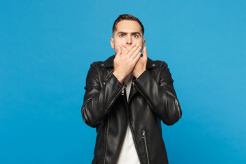 Young sad frustrated worried unshaven man in black jacket white t-shirt looking camera isolated on blue wall background studio portrait. People sincere emotions lifestyle concept. Mock up copy space.