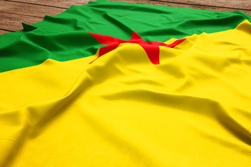 Flag of French Guiana on a wooden desk background. Silk flag top view.