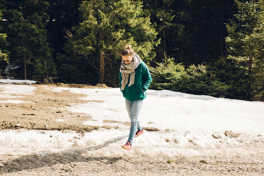 Female walker on a snowy road surrounded by pine trees