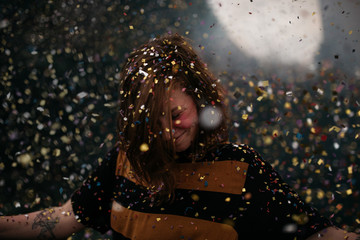 a girl dancing under a confetti rain at a festival