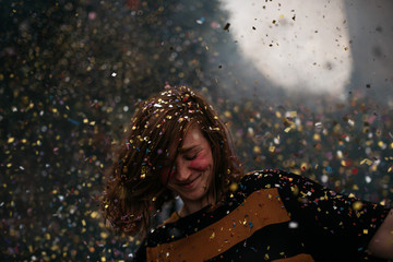 a girl dancing under a confetti rain at a festival