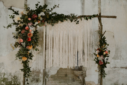 Bohemian handmade macrame backdrop with flowers for wedding ceremony in old abandoned chateau in Normandy