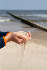 a little boy slowly lets sand flow through his hands scattered by the wind.