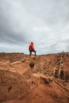 male hiker in red jacket standing on top of a bizzare mountain landscape, kyrgyzstan