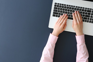 Feminine freelance workspace concept. Woman's hands typing on white laptopp with black keyboard,...