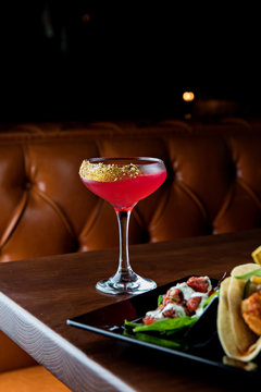 Pink cocktail with gold garnish