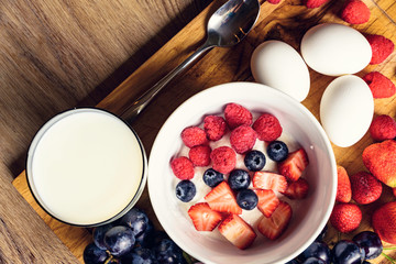 Healthy breakfast fruits on yogurt glass of milk and boiled eggs on wooden