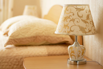 Lamp for reading on a bedside table against the background of a cozy interior of the bedroom....