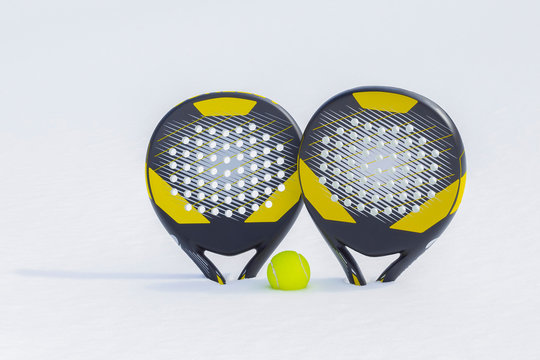 The ball and two beach tennis rackets are thrust in a snow snowdrift.