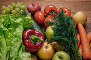 Various fresh vegetables and fruits on a wooden oak table.