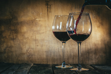 Fototapeta na wymiar Red wine in glasses on rustic background, copy space