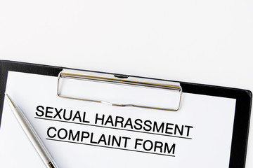 Sexual Harassment Complaint Form on attached on Clip board and pen on white background