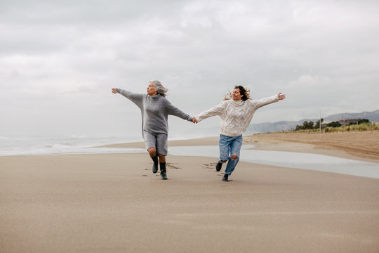 Active senior woman and her daughter enjoying on the beach in winter.