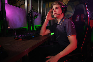 Professional young caucasian gamer playing online on his PC. He upset because of losing the game