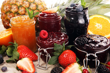 assortment of jams, seasonal berries, plums, mint and fruits in glass jar