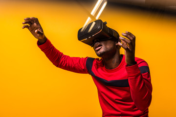 Black happy man using VR glasses over a yellow background