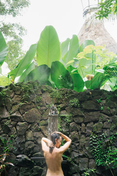 Nude woman taking shower in tropical Spa
