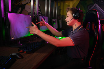 Professional young caucasian gamer playing online on his PC. He upset because of losing the game