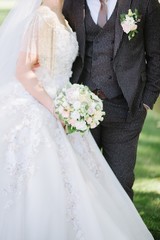 Bride in a wedding dress holding a wedding bouquet in her hands close-up