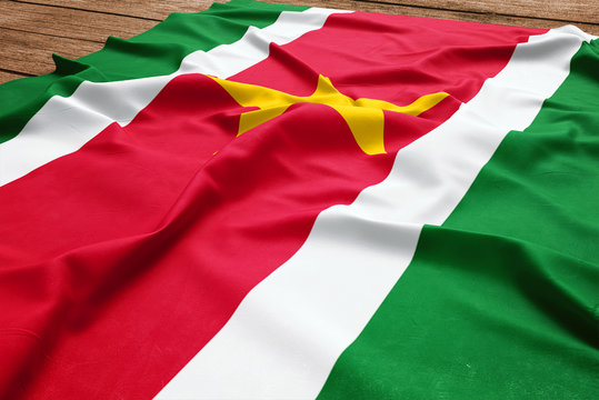 Flag of Suriname on a wooden desk background. Silk Surinamer flag top view.