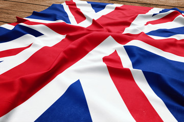 Flag of United Kingdom on a wooden desk background. Silk British flag top view.