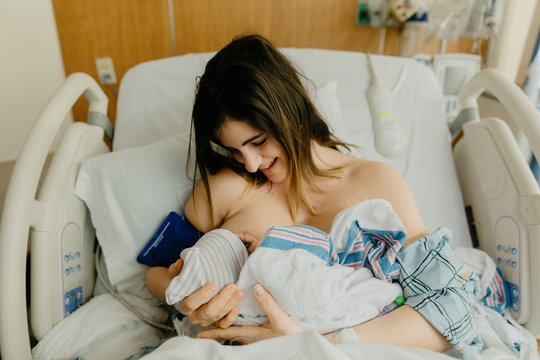 Mother Breast Feeding her Newborn in the Hospital Smiling