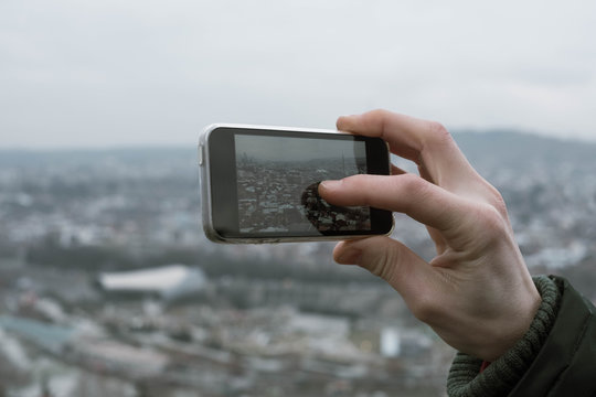 Young man takes pictures of the city from above with his phone