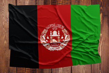 Flag of Afghanistan on a wooden table background. Wrinkled Afghan flag top view.