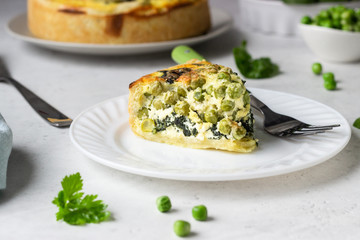 Spinach and green pea quiche, tart or pie with fresh ingredients for baking. Light grey background, copy space. 