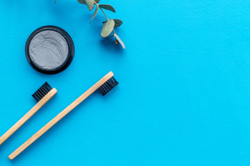 Eco materials concept with bamboo tooth brush and toothpaste with bamboo carbon on blue background top view copy space