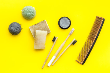 eco friendly bamboo tooth brush and carbon toothpaste, comb, organic soap on yellow background top