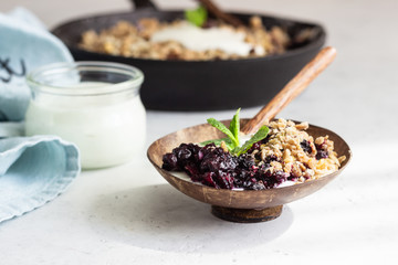 Oatmeal crumble in cast iron pan with fresh blueberry and natural yogurt. Healthy food concept. 