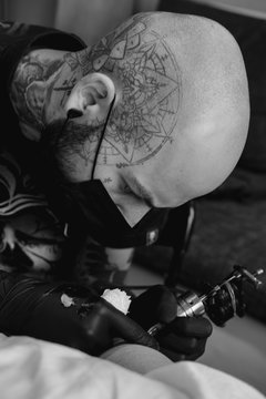 Tattoo artist drawing on client's skin