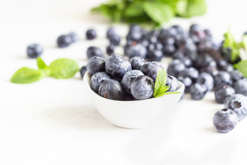 Freshly picked blueberries in a white ceramic bowl. Selective focus, copy space for text. 
