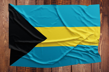 Flag of Bahamas on a wooden table background. Wrinkled Bahamian flag top view.