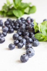 Fresh blueberries and mint leaves on light grey stone background. Organic food for healthy lifestyle. 