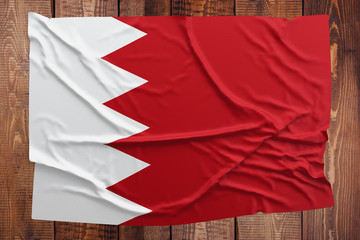 Flag of Bahrain on a wooden table background. Wrinkled Bahraini flag top view.