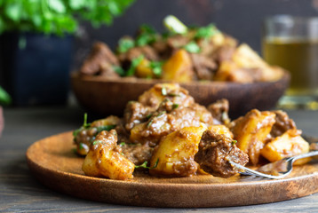 Meat stew with potatoes and parsley in wooden dish. Traditional Portuguese meat stew. Wooden...