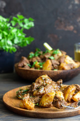 Meat stew with potatoes and parsley in wooden dish. Traditional Portuguese meat stew. Wooden background.