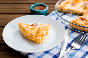 Rustic large tart and piece with cloth on a wooden table, view from above, close-up
