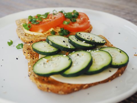 A healthy, hearty vegetable toast lunch sandwich with tomatoes, cucumbers and chives