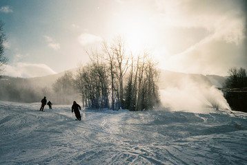Three skiers weave down a freshly coated ski slope in the Maine mountains.