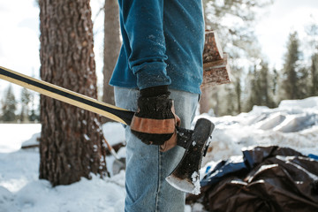 Man holding splitting maul and firewood.