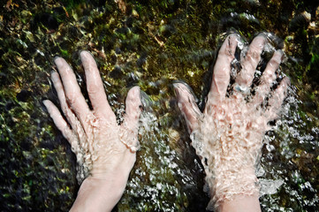 Hands in the water of a running stream