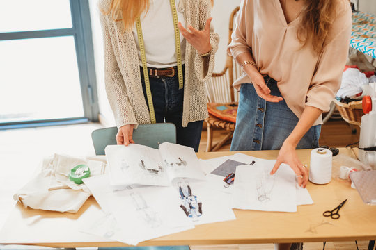 Two young female fashion designers working together at the design studio
