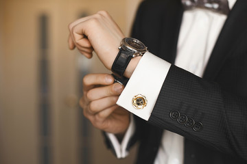 Close view of the luxury watches on the hand of a handsome businessman in a tuxedo and in a shirt with cufflinks
